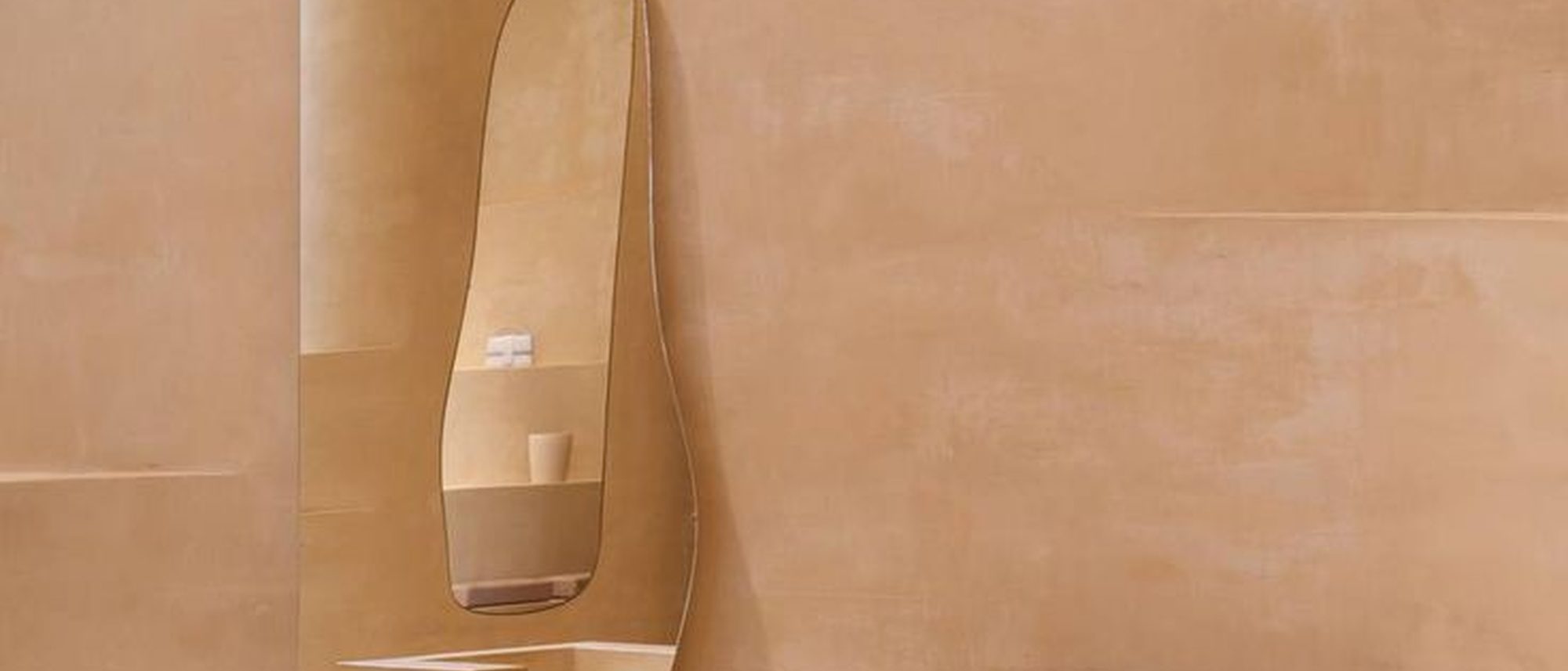 Tadelakt plaster shower wall with a smooth, burnished terracotta finish