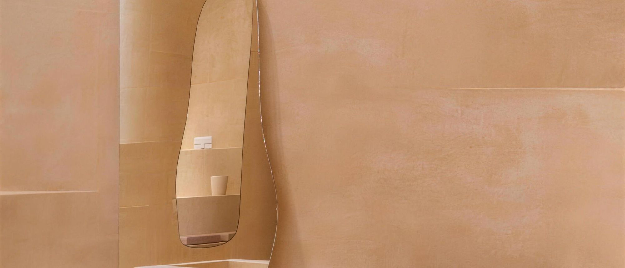 Tadelakt plaster shower wall with a smooth, burnished terracotta finish