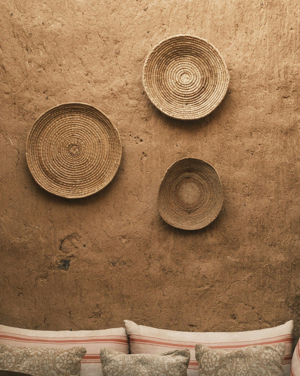 Hand-textured clay plaster wall hung with woven baskets